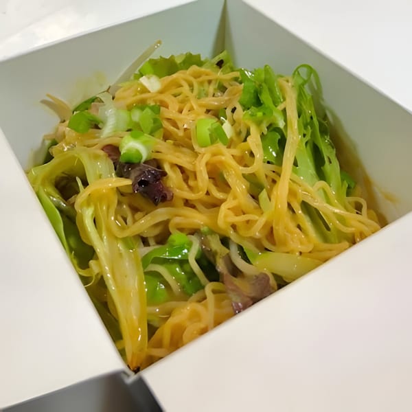 Bobby Wong's Chinese noodles with green vegetables and scallions in a white takeout box.