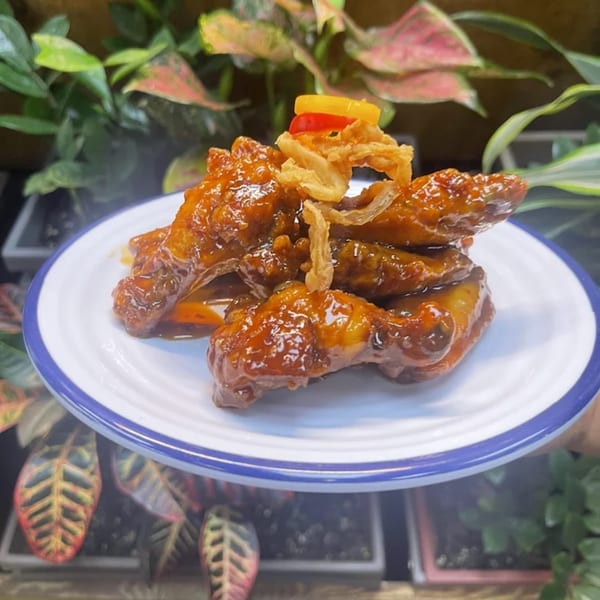 Bobby Wong's Chinese chicken wings with crispy fried onions and bell peppers on a white plate.