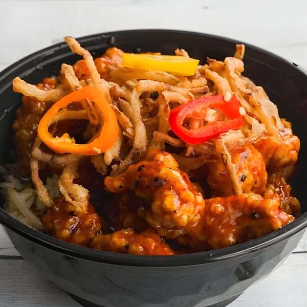 Bobby Wong's Chinese dish with orange chicken, crispy fried onions, and bell peppers in a black bowl.