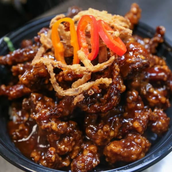 Bobby Wong's Chinese dish with crispy fried chicken in a dark sauce, topped with fried onions and bell peppers.