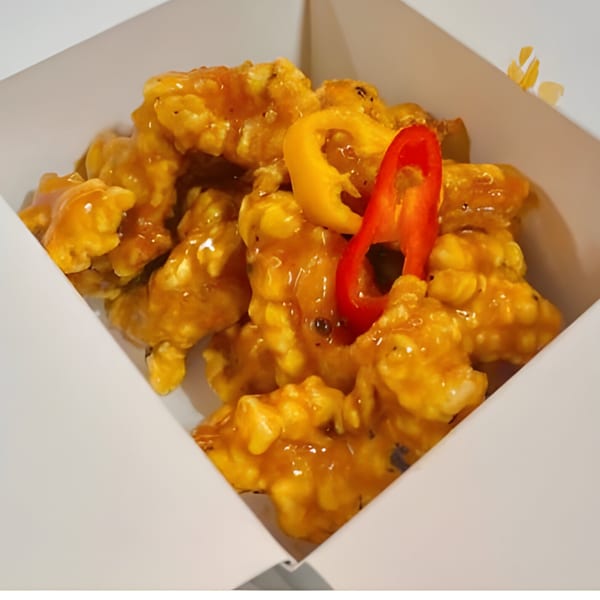 Bobby Wong's sweet and sour chicken with bell peppers in a white takeout box.
